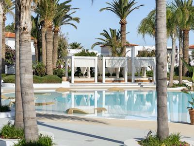 Pool area with white pavilion and palm trees in a sunny hotel setting