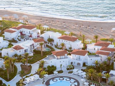 Hotelový komplex s bílými budovami a červenými střechami u pláže a moře