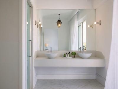 Moderní koupelna s velkým zrcadlem, dvěma umyvadly a světlými stěnami.