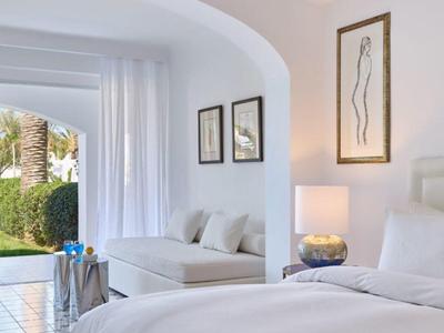 Elegantní hotelový pokoj s pohodlnou postelí, pohovkou a výhledem na zahradu.