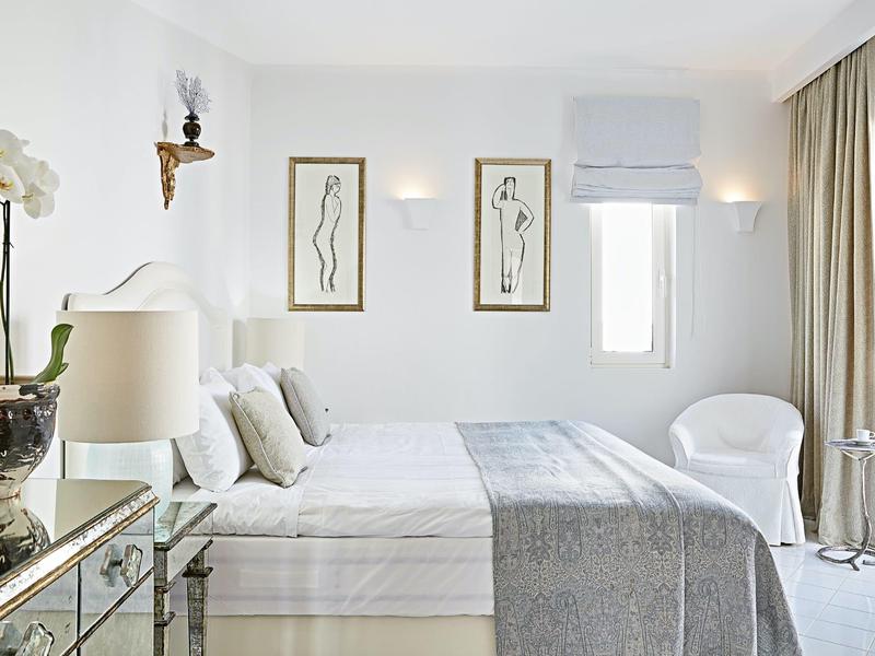 Světý, minimalisticky zařízený hotelový pokoj s manželskou postelí, moderním dekorací a dostatkem přirozeného světla.