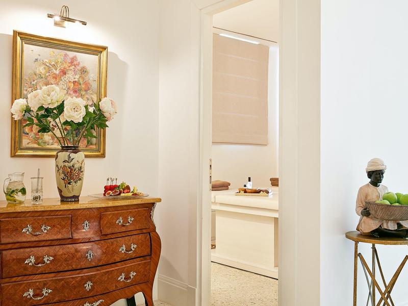 Elegantní vstupní prostor s antickým komodou, květinovými vázy a uměleckými díly na zdi.