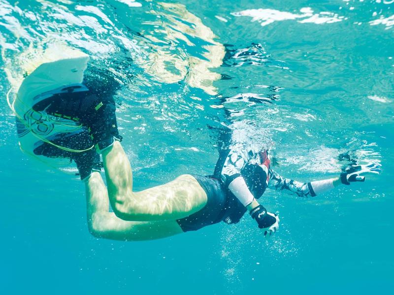 Osoba potápí v čisté vodě s šnorchlem a ploutvemi.