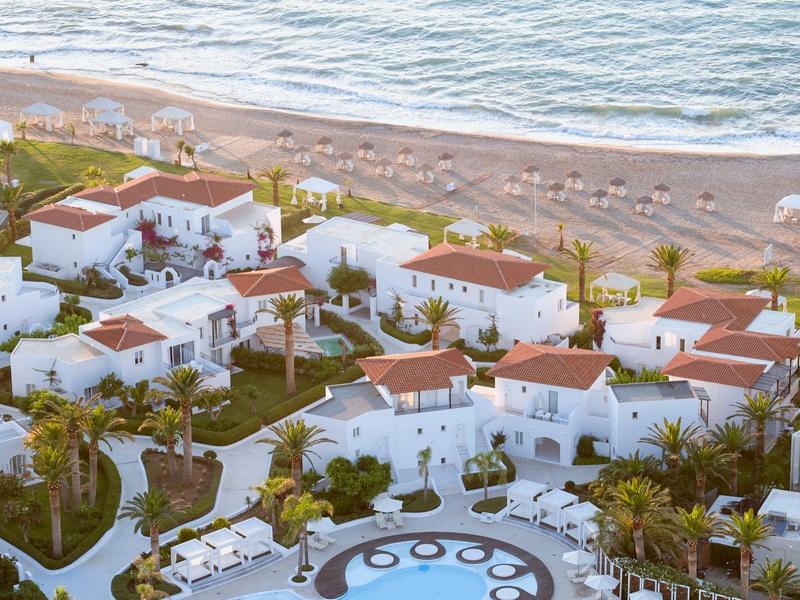 Hotelový komplex s bílými budovami a červenými střechami u pláže a moře