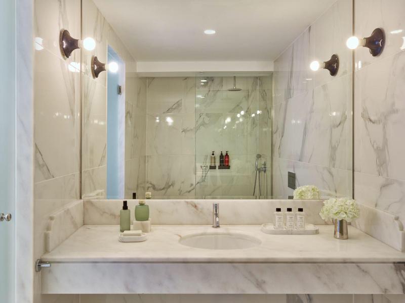 Moderní koupelna s bílým mramorem, umyvadlem a osvětleným zrcadlem.