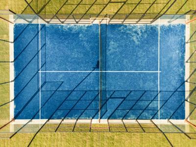 Vista aerea di un campo da tennis blu con linee circostanti e bordo verde