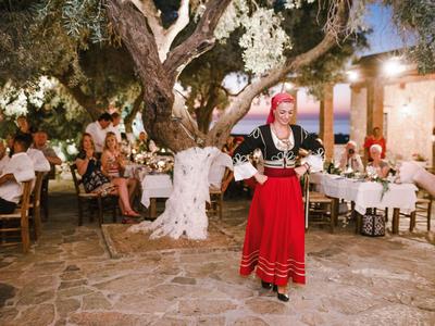 Una donna in costume tradizionale balla davanti a un albero con decorazioni bianche in un ristorante all'aperto.