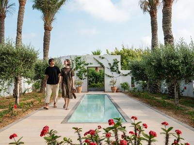 Coppia che cammina accanto a una piscina stretta con palme e fiori nel giardino dell'hotel.