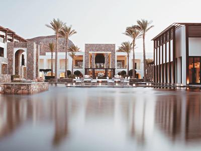 Luxuriöses Resort mit Pool, Palmen und moderner Architektur bei Sonnenuntergang.