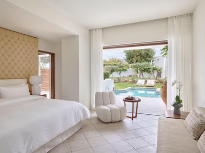 Helles Schlafzimmer mit gemütlichem Sessel und Blick auf Pool und Garten.