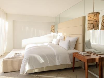 Helles Hotelzimmer mit großem Bett, weißen Bettwäsche und sideboards neben dem Bett.