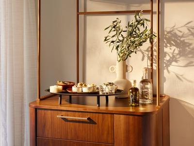 Eleganter Holztisch mit Serviertablett, Vasen und dekorativen Elementen im warmen Licht.