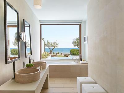 Modernes Badezimmer mit freistehender Badewanne und Meerblick durch großes Fenster.