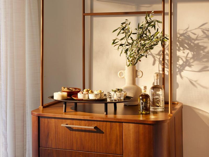 Eleganter Holztisch mit Serviertablett, Vasen und dekorativen Elementen im warmen Licht.