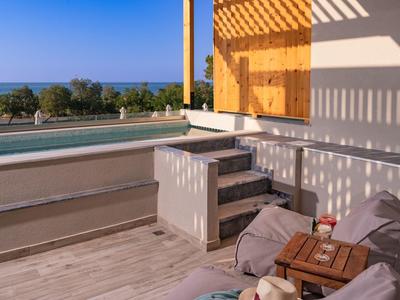 Terasa s bazénem, posezením a výhledem na moře za jasné oblohy.