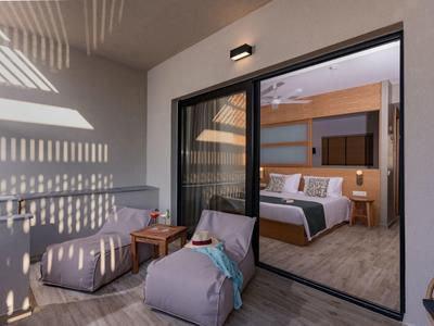 Moderní balkon s sedacími vaky, dřevěným stolem a výhledem do útulné ložnice.