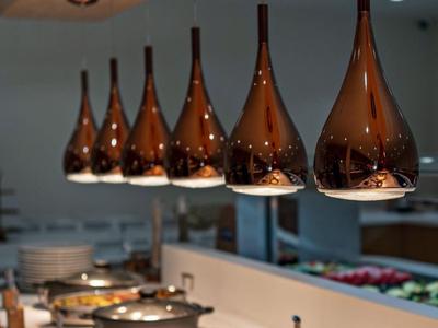 Řada moderních závěsných svítidel nad bufetem s teplými pokrmy v bufetové restauraci.