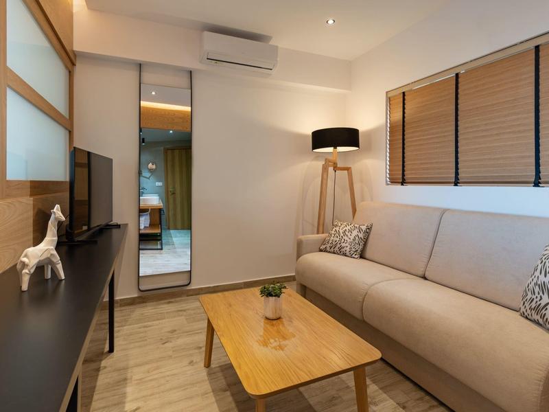 Moderní obývací pokoj s pohovkou, dřevěným stolem, stojací lampou a zrcadlem na stěně.