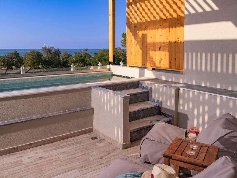 Terasa s bazénem, posezením a výhledem na moře za jasné oblohy.