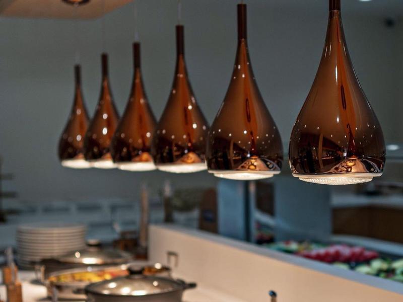 Řada moderních závěsných svítidel nad bufetem s teplými pokrmy v bufetové restauraci.