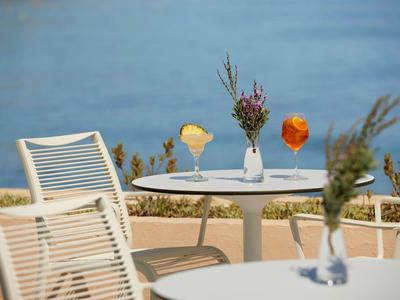 Terrasse avec tables blanches, chaises et vases avec fleurs avec vue sur l'eau