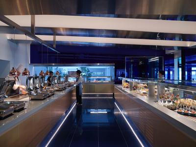 Nowoczesne wnętrze bufetu z niebieskim oświetleniem i ladami z jedzeniem.