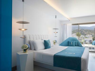 Elegancki pokój hotelowy z podwójnym łóżkiem, białe i niebieskie dekoracje, widok na basen.