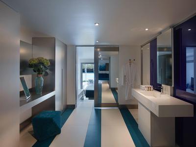 Nowoczesny korytarz z lustrem, niebieskimi siedziskami i białą umywalką.