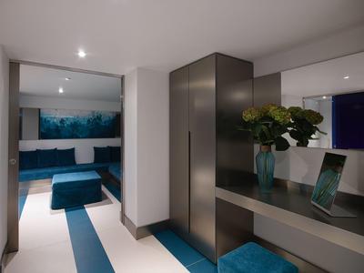 Nowoczesny kącik wypoczynkowy z niebieskimi meblami i roślinną dekoracją w jasnej przestrzeni.