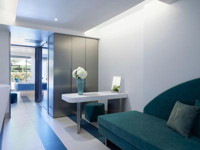 Nowoczesne wnętrze z zieloną sofą, białym stołem i dużą szarą szafą.