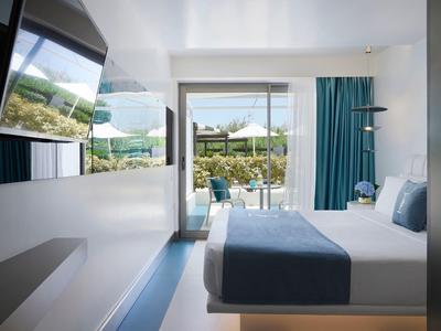 Nowoczesny pokój hotelowy z podwójnym łóżkiem i widokiem na taras i ogród.