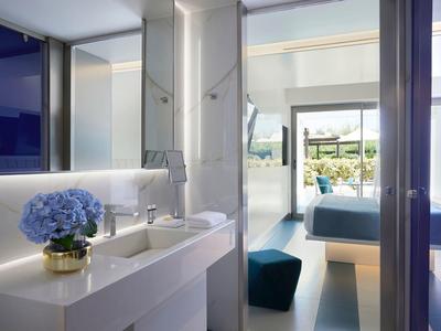 Nowoczesny wnętrze pokoju hotelowego z niebieskimi dekoracjami i wyjściem na słoneczny taras.