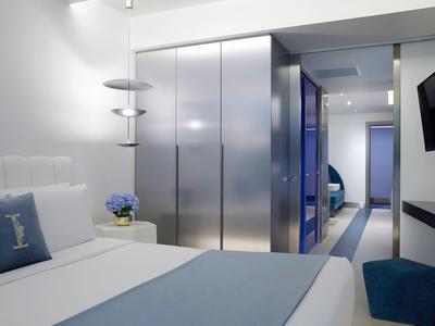 Nowoczesny pokój hotelowy z podwójnym łóżkiem, niebieskimi dekoracjami i minimalistycznymi meblami.