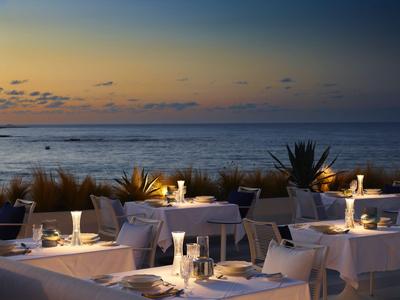 Dîner élégant en plein air avec éclairage de table et vue sur l'océan au coucher du soleil.