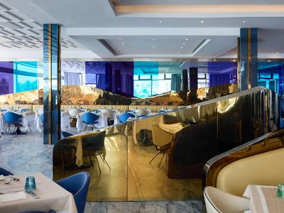 Intérieur moderne de restaurant d'hôtel avec accents bleus et cloisons dorées réfléchissantes.