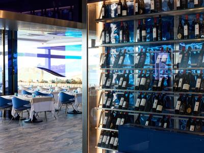 Restaurant d'hôtel avec casier à vin moderne et espace de sièges élégant avec des chaises bleues et blanches.