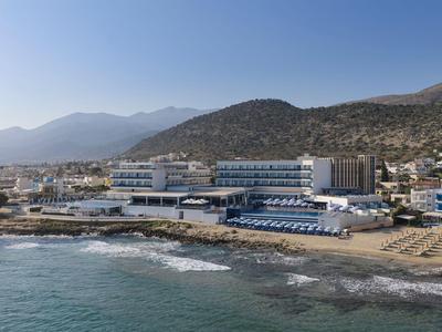 Hôtel côtier avec plage et vue sur la montagne sous un ciel clair.