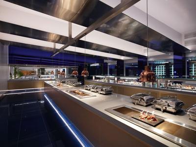 Espace repas moderne d'hôtel avec buffet et éclairage élégant la nuit.