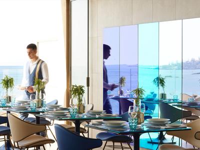 Salle à manger moderne avec vue sur la mer à travers de grandes fenêtres et mobilier élégant.