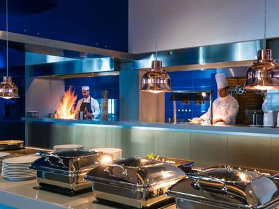 Cuisine d'hôtel moderne avec deux chefs et station de buffet sous des lumières chaudes.