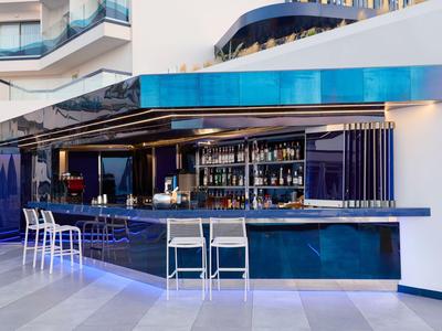 Espace bar d'hôtel moderne avec carreaux bleus et chaises blanches.