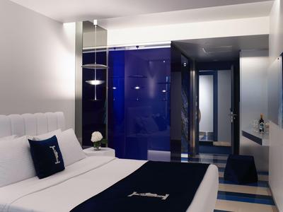 Chambre d’hôtel moderne avec lit blanc, jeté sombre et accents bleus dans un design épuré.