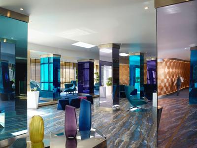 Intérieur d'hôtel moderne avec accents de verre coloré, miroirs et lumière naturelle.