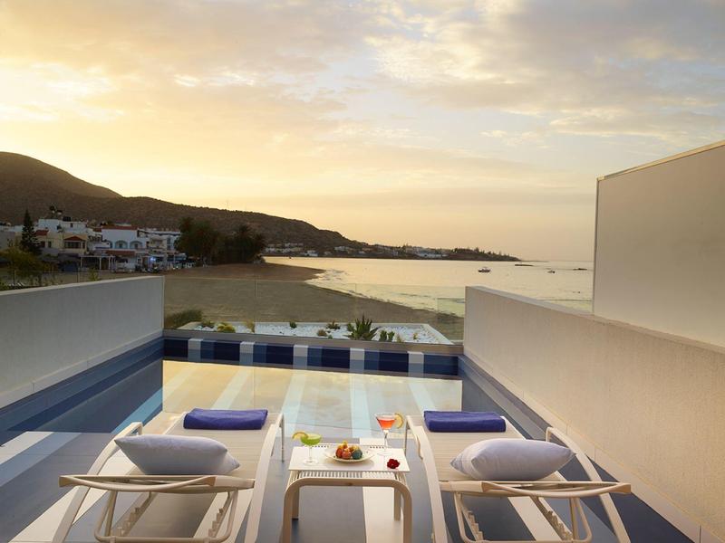 Taras z basenem i widokiem na morze o zachodzie słońca.