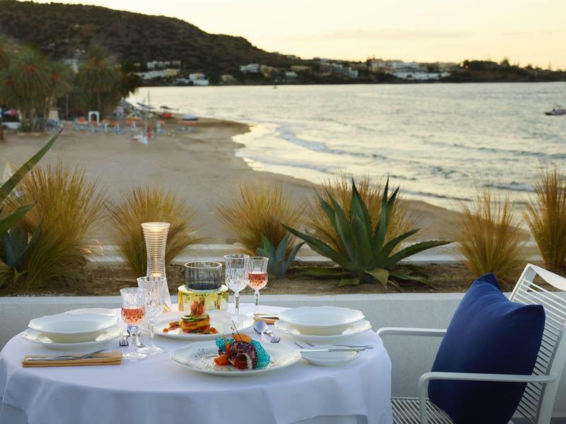 Elegancki stół nad morzem z widokiem na plażę i wzgórza o zachodzie słońca.