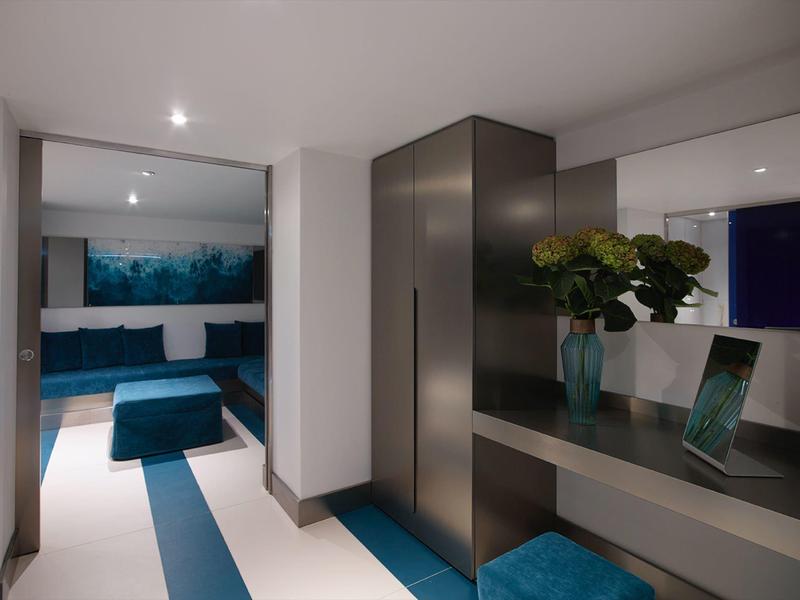 Nowoczesny kącik wypoczynkowy z niebieskimi meblami i roślinną dekoracją w jasnej przestrzeni.