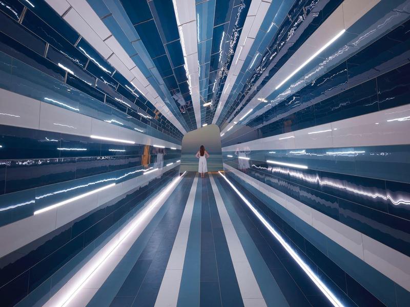 Nowoczesna lobby hotelowa z długimi, paskami świetlnymi i refleksyjnymi powierzchniami.