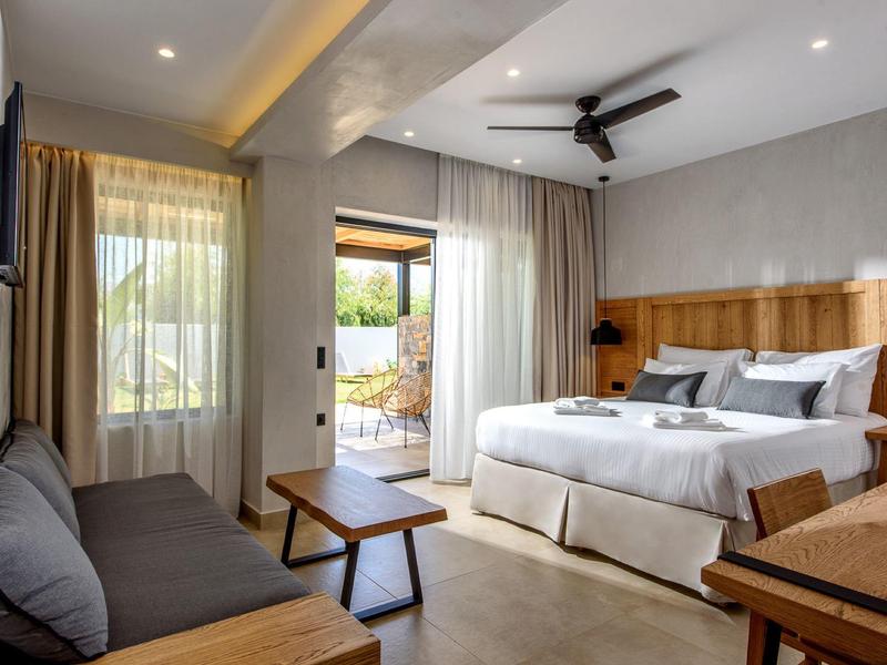 Moderne hotelkamer met tweepersoonsbed, bank, tv en toegang tot een terras met uitzicht.