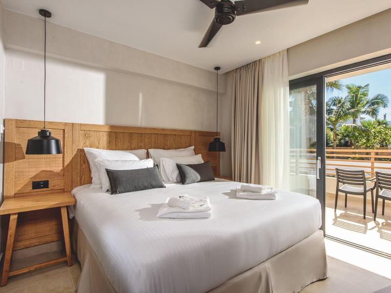 Moderne slaapkamer met tweepersoonsbed, houten meubels en balkon met zithoek.