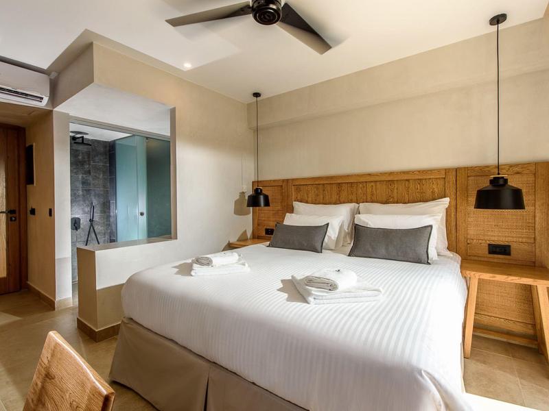 Moderne hotelkamer met groot tweepersoonsbed, houten meubels en stijlvolle verlichting.